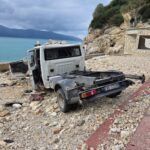 video/-kamioni-del-nga-rruga-dhe-perfundon-afer-bregut-te-detit-ne-vlore,-plagoset-rende-shoferi