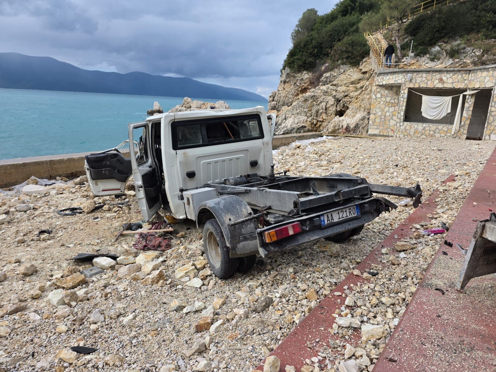 video/-kamioni-del-nga-rruga-dhe-perfundon-afer-bregut-te-detit-ne-vlore,-plagoset-rende-shoferi